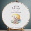 Cross stitch embroidery of a personalized sleeping bunny birth announcement displayed in a wooden hoop with custom newborn details