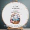 Cross stitch embroidery of a personalized baby girl birth announcement with a sleeping bunny displayed in a wooden hoop