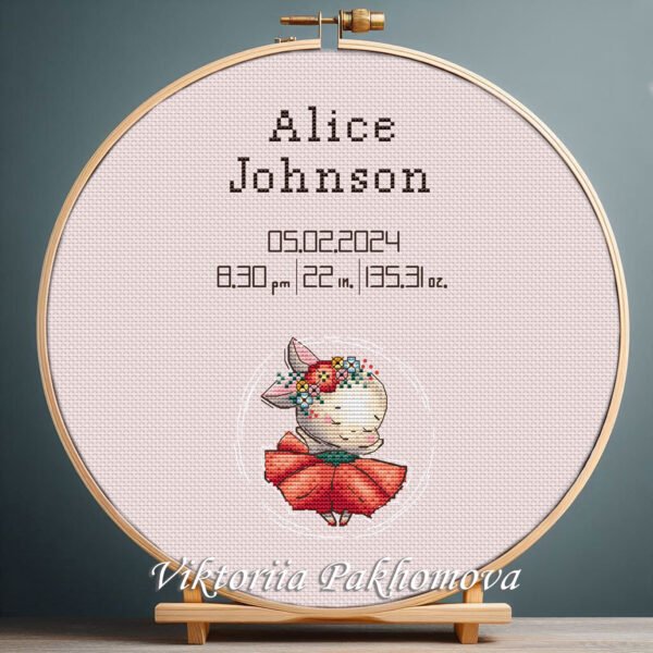 Cross stitch embroidery of a personalized dancing bunny birth stats design displayed in a wooden hoop