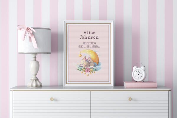 Framed sleeping bunny birth announcement cross stitch featuring personalized name, date and stats for baby girl nursery décor.