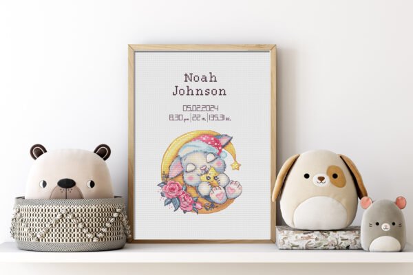 Framed sleeping bunny birth announcement cross stitch featuring personalized name, date and stats for nursery décor.