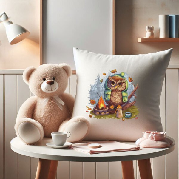 Cross stitch embroidery of a camping owl sitting by a campfire with autumn leaves on decorative pillow in kids room