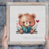 Framed cross stitch of a woodland bear reading a book with cozy floral accents