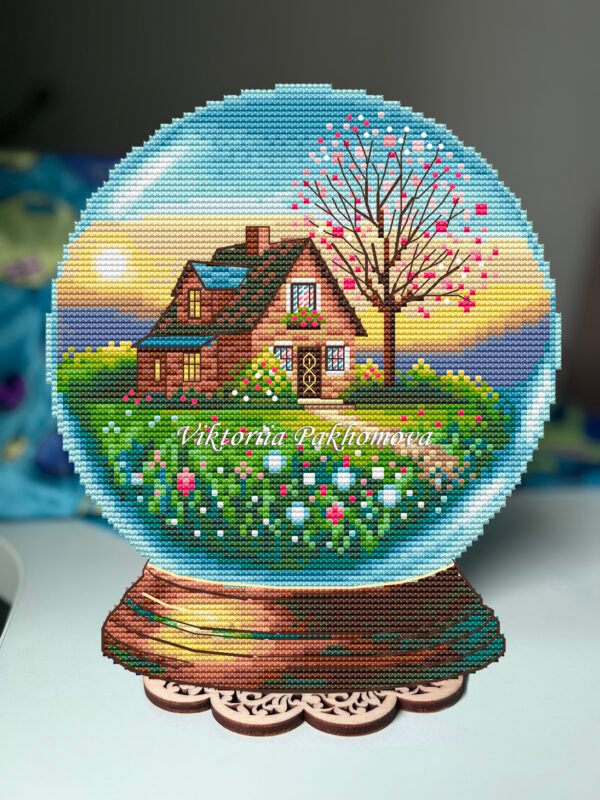 Plastic canvas cross stitch of a glass ball with a spring landscape, small house and colorful garden details