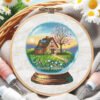 Cross stitch embroidery of a spring glass ball scene with a garden house and colorful flowers in a wooden hoop