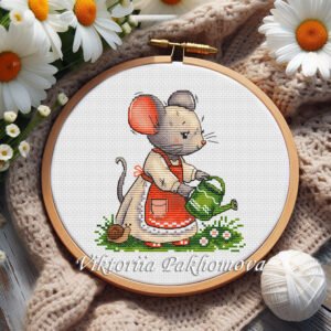 Cottagecore mouse gardener cross stitch pattern in a wooden hoop, surrounded by daisies, yarn, and cozy knitted fabric.