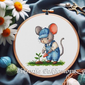 Cottagecore baby mouse gardener cross stitch pattern in a wooden hoop, surrounded by daisies, yarn, and embroidery scissors.